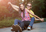 Young couple in love sitting on a skateboard outdoors