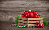 Christmas balls in box with fir on wooden board