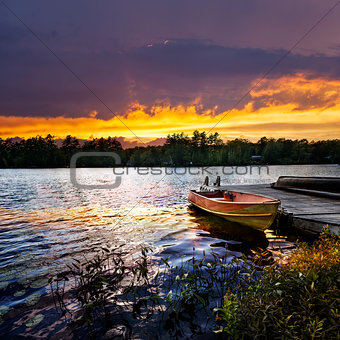 Boat docked on lake at sunset