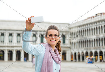 Smiling woman tourist taking a photo on St. Mark's Square