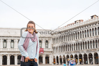 Happy woman tourist with hands in pockets on St. Mark's Square