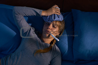 Girl With Fever Holds Thermometer In Mouth At Night