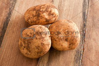 Three Unwashed Potatoes on a Wooden Table