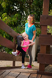 Happy young mother and daughter standing on wood bridge at beach