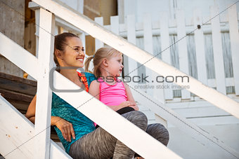 Smiling mother in profile on beach house steps with child