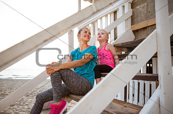 Mother and daughter sitting and talking on beach-house steps