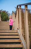 Child standing on wooden steps at beach looking down