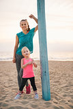 Mother leaning against flagpole standing behind daughter