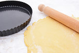 Baking tin next to shortcrust pastry and rolling pin