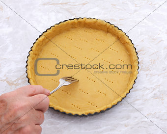 Woman finishes pricking holes in a pastry pie crust