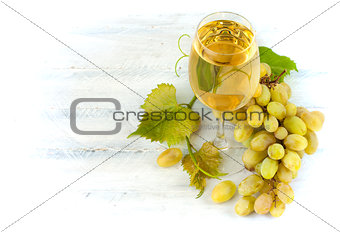 Glass white wine with grapes and leaf on wooden board