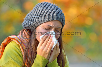 Girl  sneezing in tissue.
