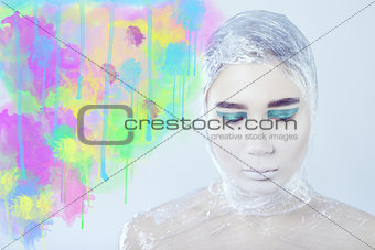 Misterous pretty woman wrapped in cellophane standing on light grey background, watercolor spots