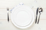 Empty plate and silverware over wooden table