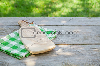 Empty garden table with cutting board over tablecloth