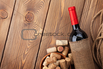 Red wine bottle and corks over wooden table background