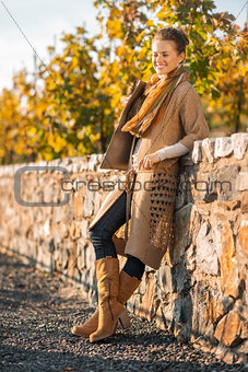 Smiling woman in comfortable clothing is standing in autumn park