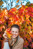 Portrait of happy woman with autumn leafs in front of foliage