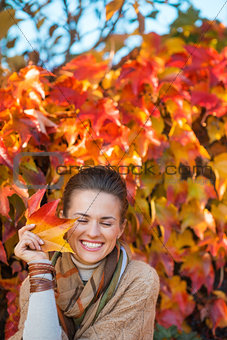 Portrait of smiling woman with autumn leafs in front of foliage