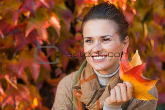 Portrait of pensive woman with leafs in front of autumn foliage