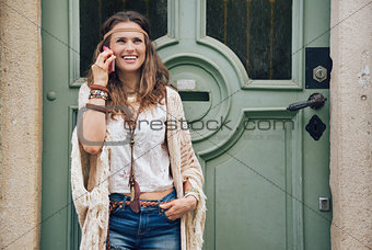 Laughing hippie woman in boho clothes talking cell phone