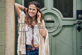 Happy woman wearing bohemian style clothes talking cell phone