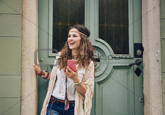 Happy trendy hipster woman with mobile phone standing outdoors