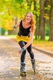 laughing girl roller-skating in the autumn park one