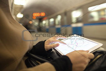 Tablet in female hands showing subway map in underground
