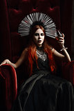 Gothic fashion: young woman sitting in chair and holding glass of wine