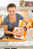 Funny woman creating pumpkin Jack-O-Lanter for Halloween party