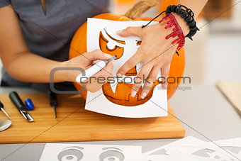 Woman using stencils to carve pumpkin Jack-O-Lantern. Closeup