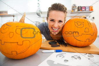 Funny young woman creating pumpkins for Halloween party