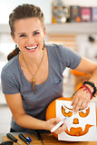 Happy young woman using stencils to carve pumpkin Jack-O-Lantern
