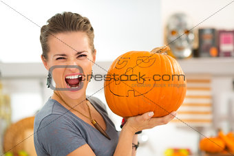 Young woman scaring with big Halloween pumpkin Jack-O-Lantern