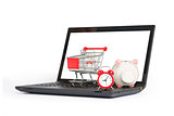 Shopping cart, clock and piggy bank on laptop