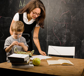 little cute boy in glasses with young real teacher, classroom studying