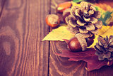 Autumnal still life with acorn pinecone and yellow leaves on wooden board