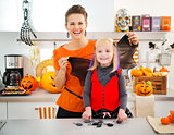 Funny halloween dressed girl with mother in kitchen