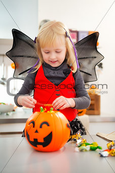 Interested girl in halloween bat costume checking candy