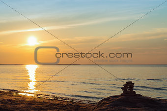 Inukshuk stones on ocean shore at sunset