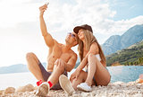 Couple sitting on a beach and taking a selfie
