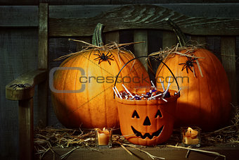 Pumpkins and spiders with candles on bench 