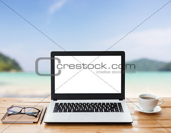laptop computer and coffee on wood workspace and mountain at sun