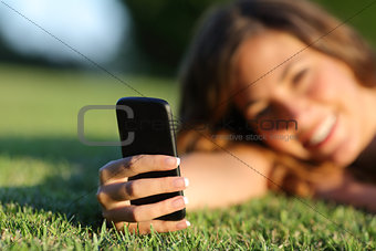 Close up of a happy teen girl hand using a smart phone on the grass