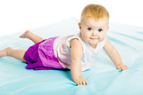 baby girl in a dress creeps on the blue coverlet