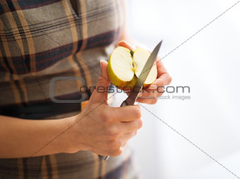 A woman's elegant hands holding a knife and cutting an apple