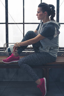 Pensive woman in workout gear looking in profile in loft gym