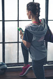 Rear view of woman holding mobile phone near window in loft gym