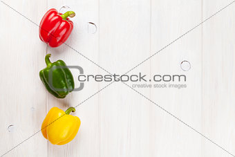 Colorful bell peppers on white wooden table